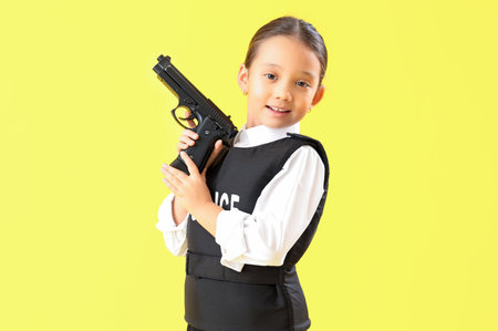 Cute little police officer with gun on yellow background. Opposite Day celebrationの写真素材