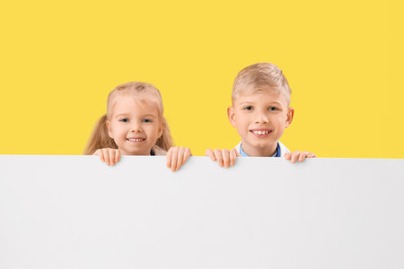 Cute little doctors with blank poster on yellow background. Opposite Day celebrationの写真素材