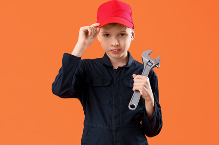 Cute little mechanic with wrench on orange background. Opposite Day celebrationの写真素材