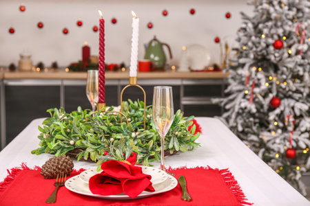 Table setting with Christmas mistletoe wreath and burning candles in kitchen, closeupの写真素材
