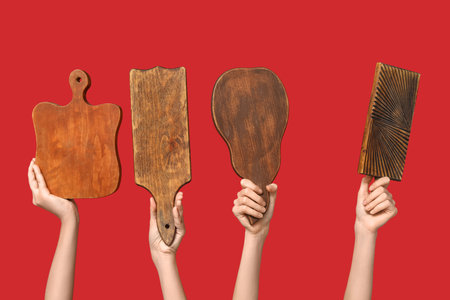 Female hands with wooden cutting boards on red backgroundの写真素材