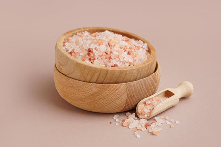 Wooden bowl and scoop with Himalayan pink salt on brown backgroundの写真素材