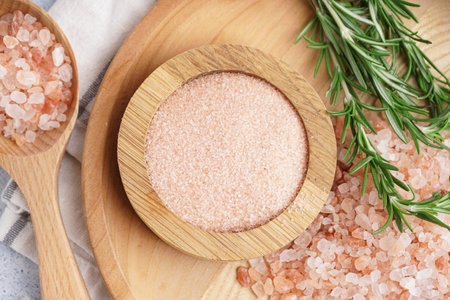 Wooden plate and spoon of Himalayan pink salt with rosemary on white background, closeupの写真素材