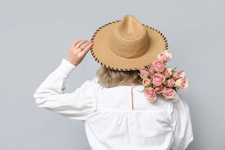 Young woman with bouquet of beautiful roses on gray backgroundの写真素材