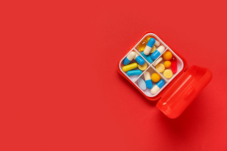 Container with different pills on red backgroundの写真素材