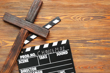 Cross with movie clapper on wooden background. Christmas story conceptの写真素材