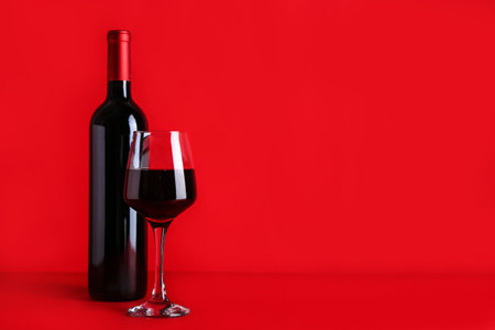 Bottle and glass of red wine on color backgroundの写真素材