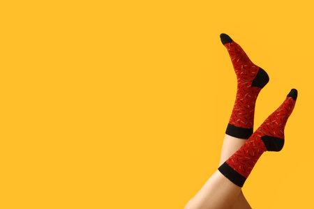 Legs of young woman in red socks on yellow backgroundの写真素材