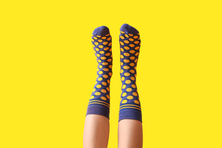 Legs of young woman in purple dotted socks on yellow backgroundの写真素材
