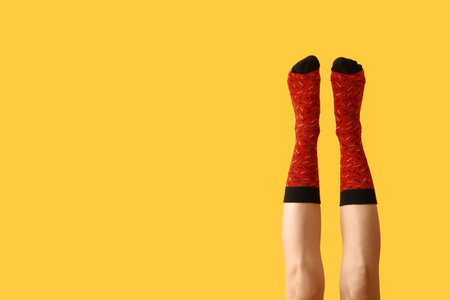 Legs of young woman in red socks on yellow backgroundの写真素材