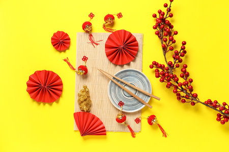 Bamboo mat with plate, chopsticks and decor on yellow background. Chinese table settingの写真素材