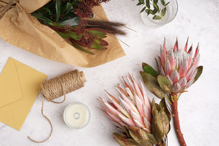Composition with beautiful pink protea flowers, threads, envelope and candle on white backgroundの写真素材