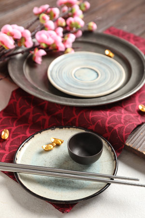 Wooden board with dishes, chopsticks and sakura branch on white background. Chinese table settingの写真素材