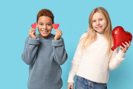 Cute little children with red paper hearts and air balloon on blue background. Valentine's day celebrationの写真素材