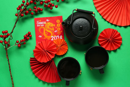 Greeting card with teapot, cups of tea and paper fans on green background. Chinese New Year celebrationの写真素材