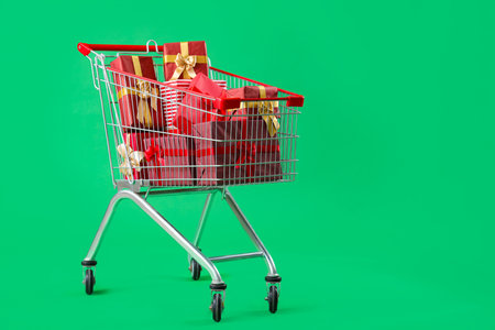 Shopping cart full of Christmas gift boxes on green backgroundの写真素材