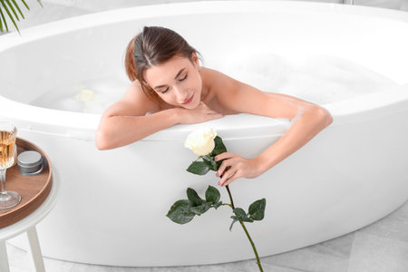 Beautiful woman with rose taking bath at homeの写真素材