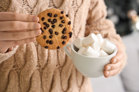 Woman holding cup of cocoa with marshmallows and cookies at home on Christmas Eve, closeupの写真素材