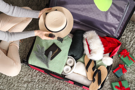Woman packing clothes, beach accessories and Christmas gifts at homeの写真素材