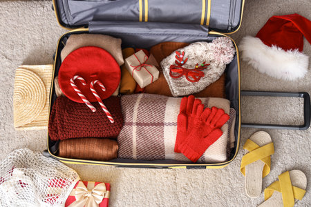 Suitcase with clothes, beach accessories and Christmas decor on floorの写真素材