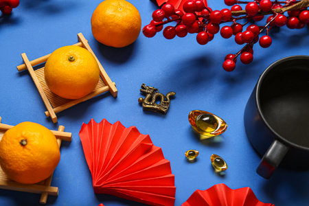 Bronze dragon figure with paper fans, tangerines and cup on blue background. Chinese New Year celebrationの写真素材