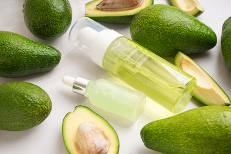 Fresh avocados and bottles of essential oil on light background, closeupの写真素材