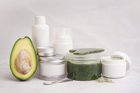 Fresh avocado and jars of cosmetic products on light backgroundの写真素材