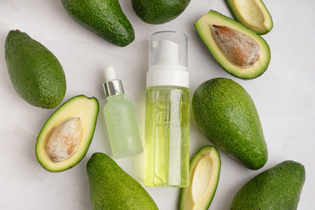 Fresh avocados and bottles of essential oil on light backgroundの写真素材