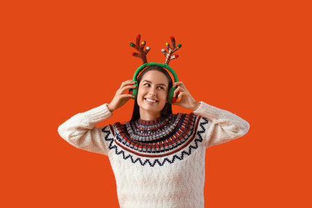 Young woman in reindeer horns on orange backgroundの写真素材