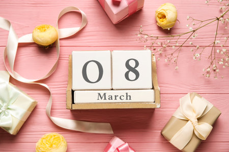 Composition with cube calendar, figure 8 made of ribbon and gift boxes on pink wooden background. International Women's Day celebrationの写真素材