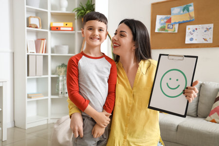 Female psychologist with paper smile and little boy in officeの写真素材