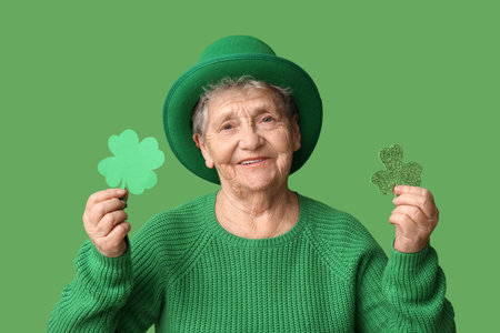 Senior woman in leprechaun hat with clover on green background. St. Patrick's Day celebrationの写真素材