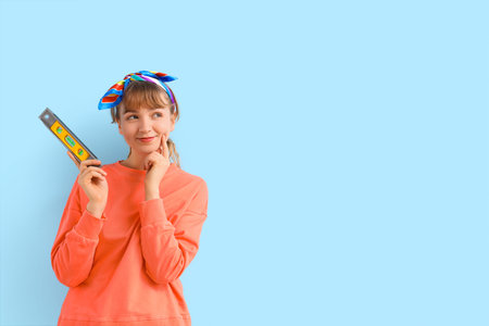 Thoughtful young woman with spirit level on blue background. Repair concept