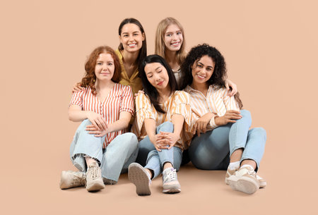 Beautiful young women sitting on beige background. Women history monthの写真素材