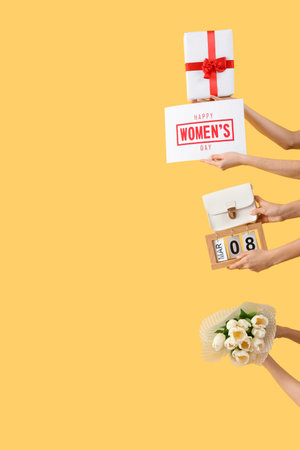 Female hands with bouquet of tulips, calendar and gift box on yellow background. International Women's Day celebrationの写真素材