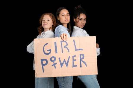 Beautiful young women holding paper with text GIRL POWER on black background. Women history monthの写真素材