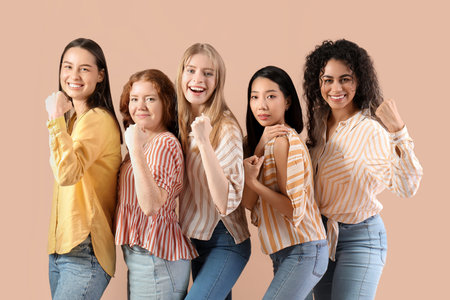 Beautiful young women with clenched fists on beige background. Women history monthの写真素材
