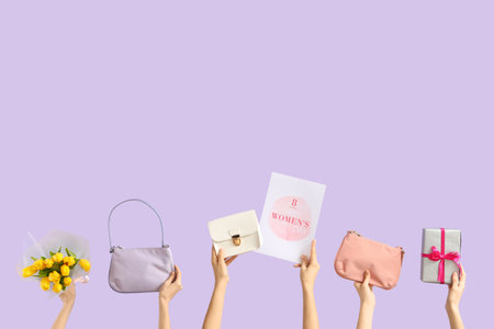 Female hands with festive postcard, bouquet of tulips and handbags on lilac background. International Women's Day celebrationの写真素材