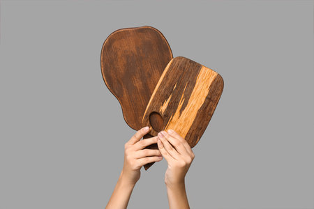 Female hands with wooden cutting boards on gray backgroundの写真素材