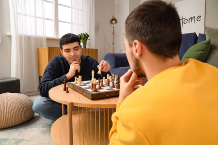 Handsome young brothers playing chess in living room