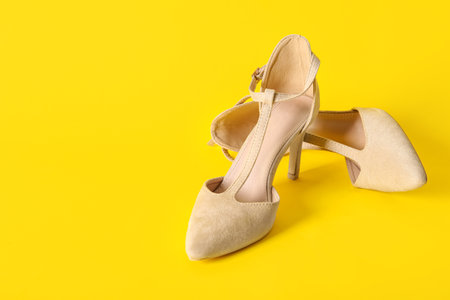 Pair of stylish female shoes on yellow backgroundの写真素材