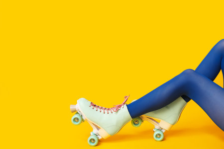 Legs of beautiful young woman in vintage roller skates on yellow backgroundの写真素材