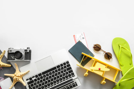 Composition with modern laptop, passport, ticket and beach accessories on light background