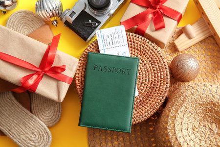 Composition with passport, ticket, beach accessories and Christmas gifts on yellow backgroundの写真素材