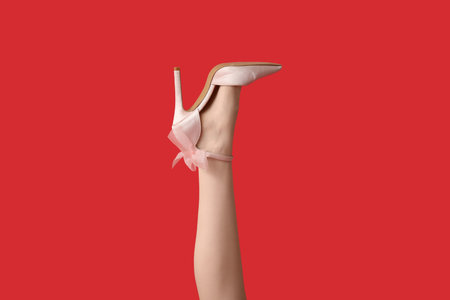 Leg of beautiful young woman in cute high heels on red background