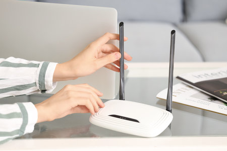 Woman with modern wi-fi router on table at home, closeupの写真素材