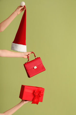 Female hands with bag, gift box and Santa hat on green background. New year shopping conceptの写真素材