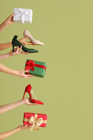 Female hands with shoes and gift boxes on green background. New year shopping conceptの写真素材