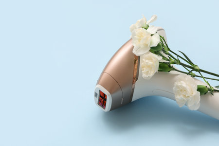 Modern photoepilator and beautiful carnation flowers on color backgroundの写真素材