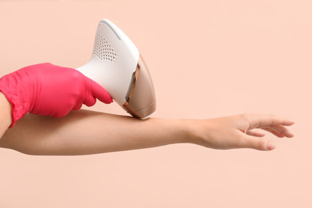 Woman using modern photoepilator on color background, closeupの写真素材